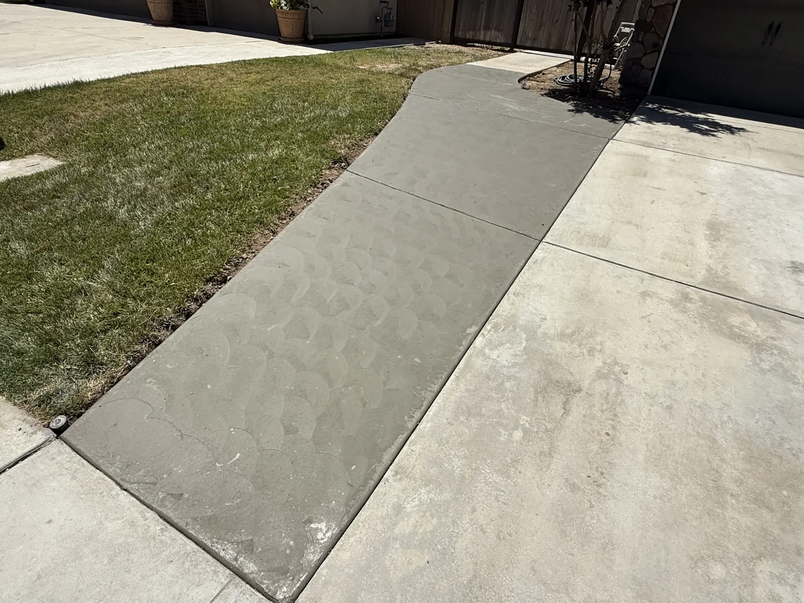 New concrete strip beside an older driveway, finished with an overlapping fan texture