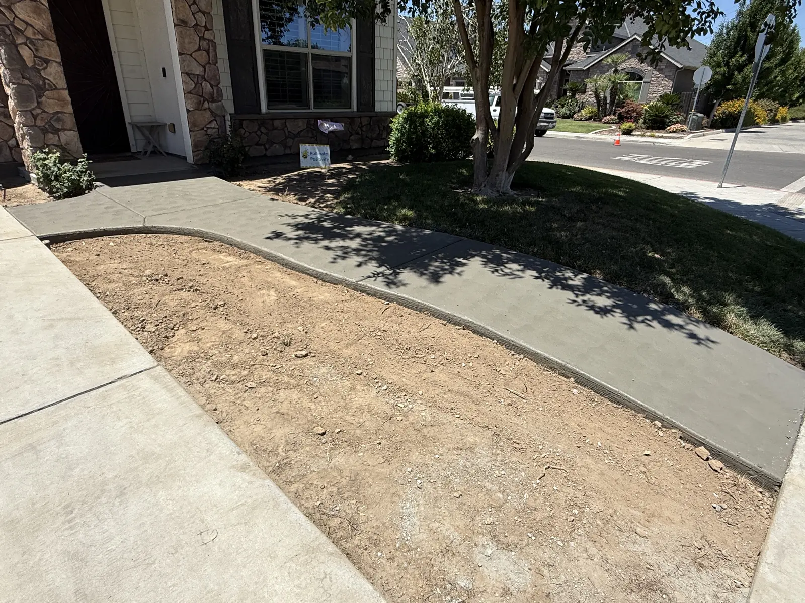 Finished walkway curving from the driveway to a stone veneer entry, edged against the lawn