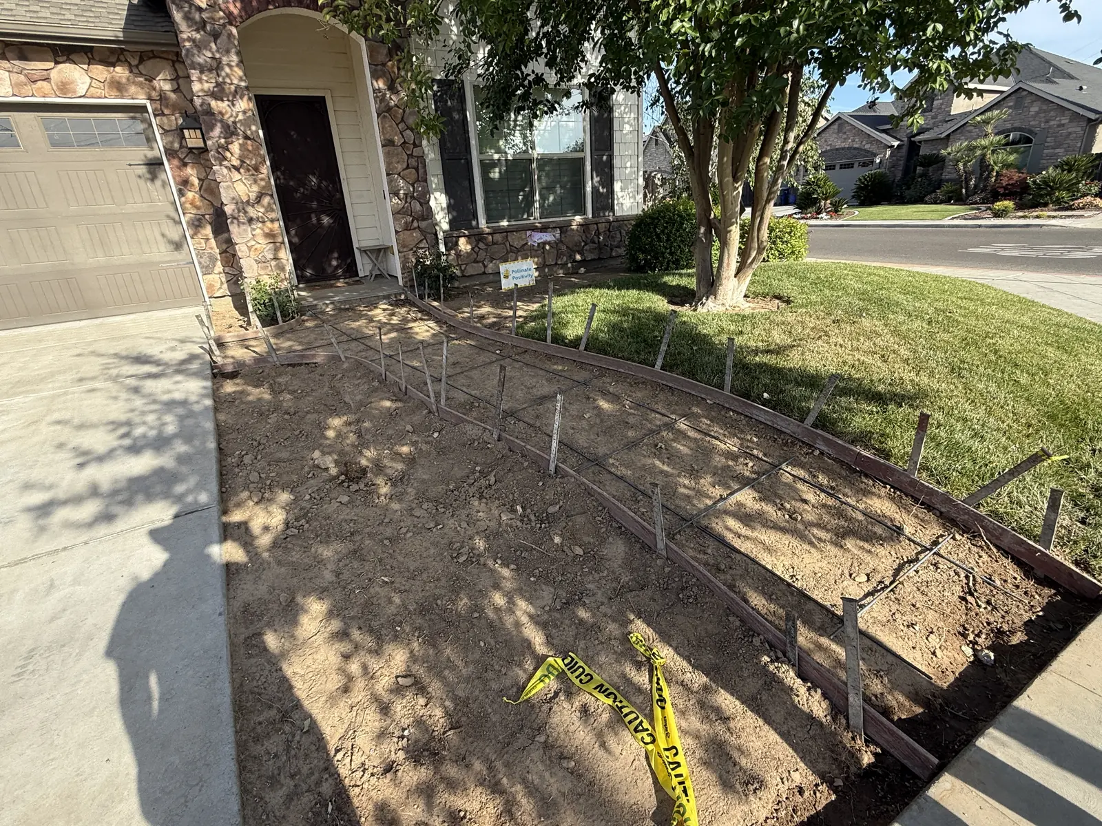 Wood forms and wire mesh staked out over graded soil where a curved entry walkway will be poured