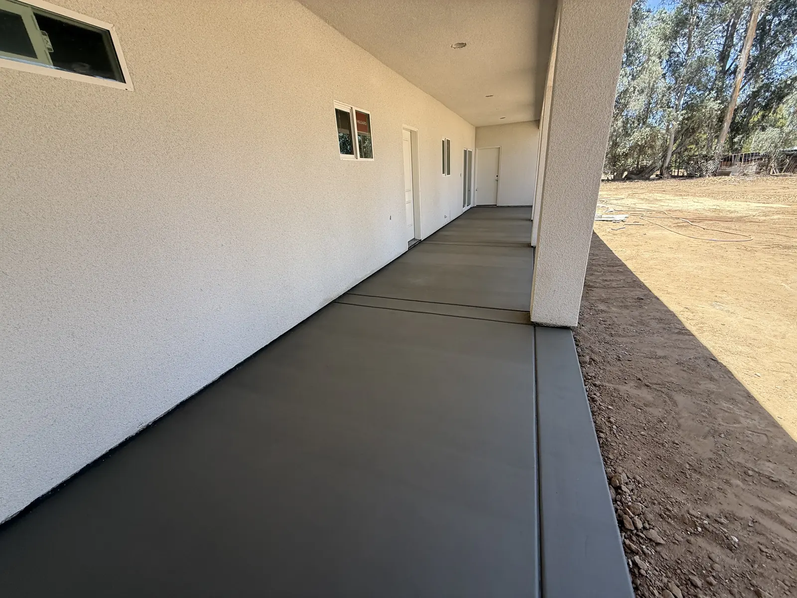 Poured walkway running the length of the covered porch, still dark from the finish