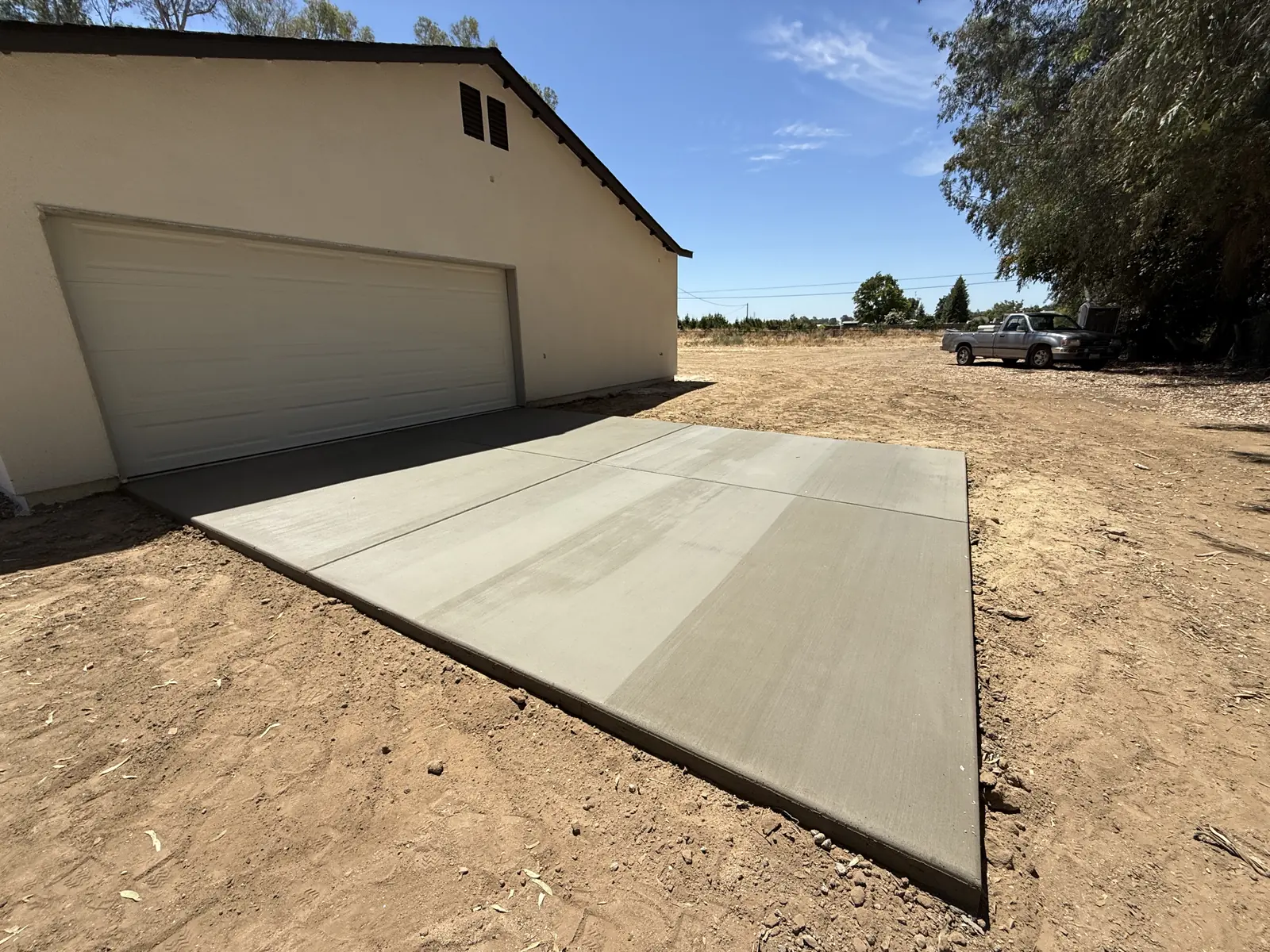 New apron poured across the garage opening, squared off against the dirt yard