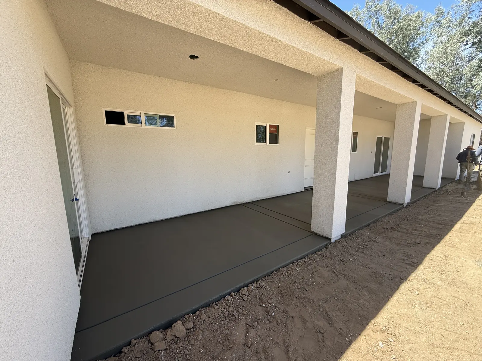Finished porch slab spanning the columns, soil banked against the fresh edge