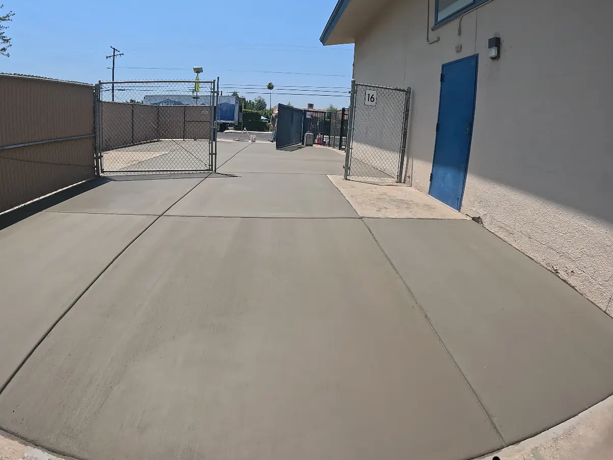 Poured concrete running the length of the classroom wall out through the open gate