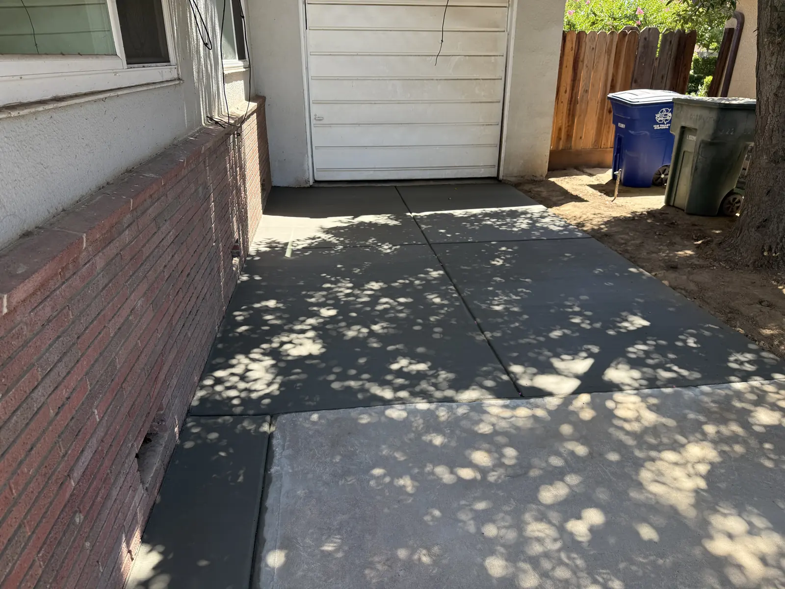 Replacement slab poured beside the brick planter, meeting the garage threshold