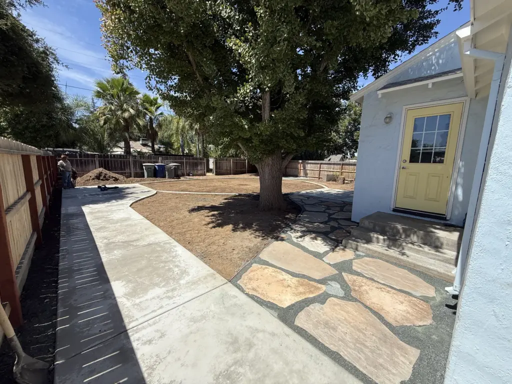 Side walkway running to a flagstone landing at the back door beneath a mature tree