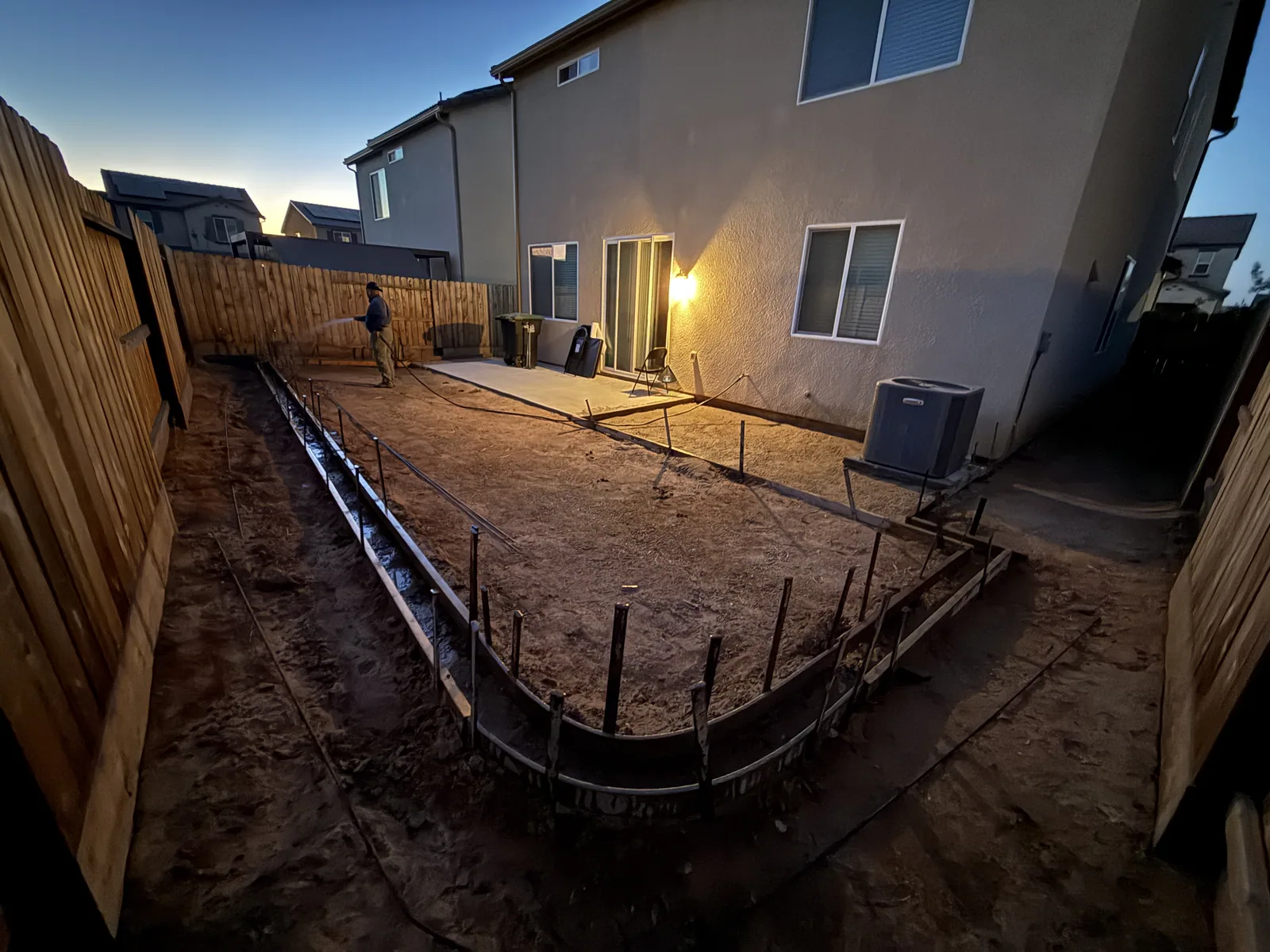 Wood forms and wire mesh staked out over graded soil where a curved entry walkway will be poured