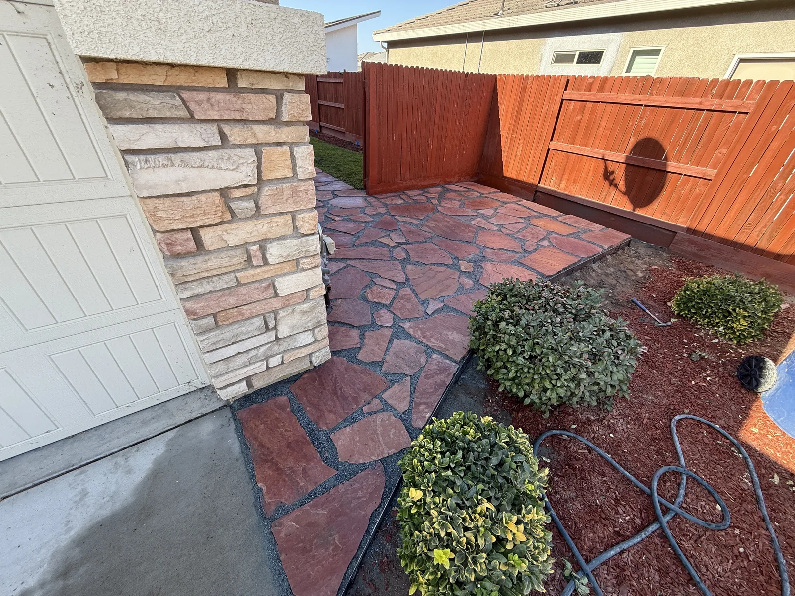 Finished walkway curving from the driveway to a stone veneer entry, edged against the lawn