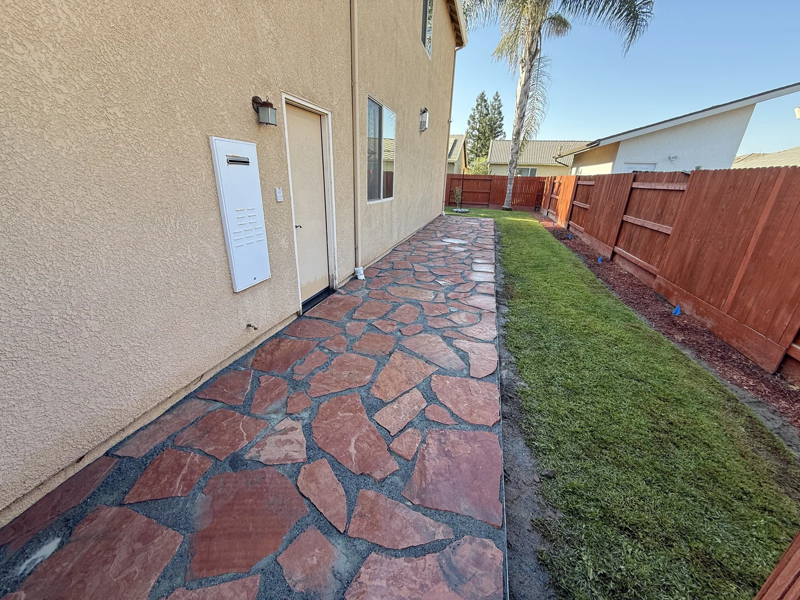 Finished walkway curving from the driveway to a stone veneer entry, edged against the lawn