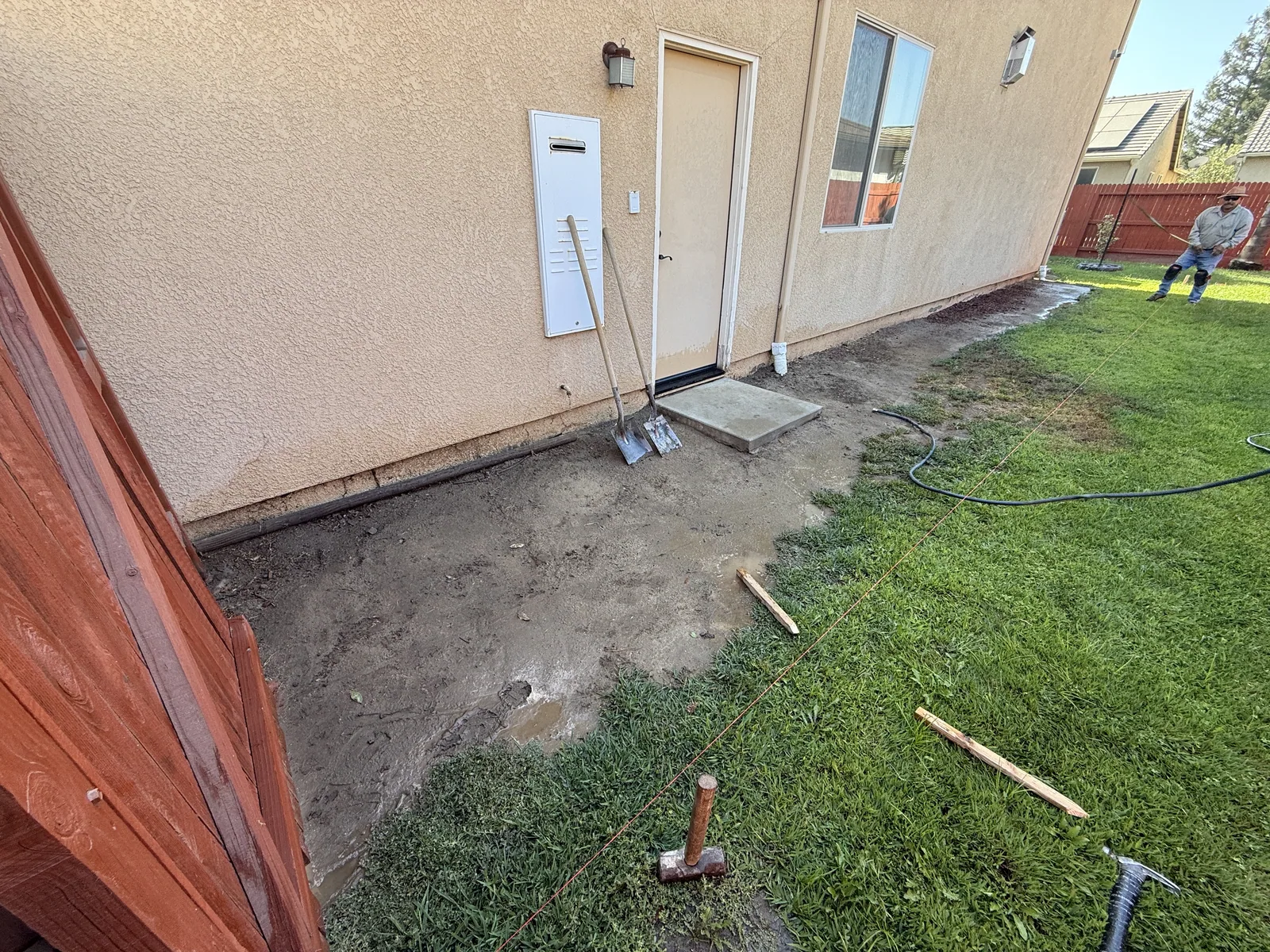 Wood forms and wire mesh staked out over graded soil where a curved entry walkway will be poured